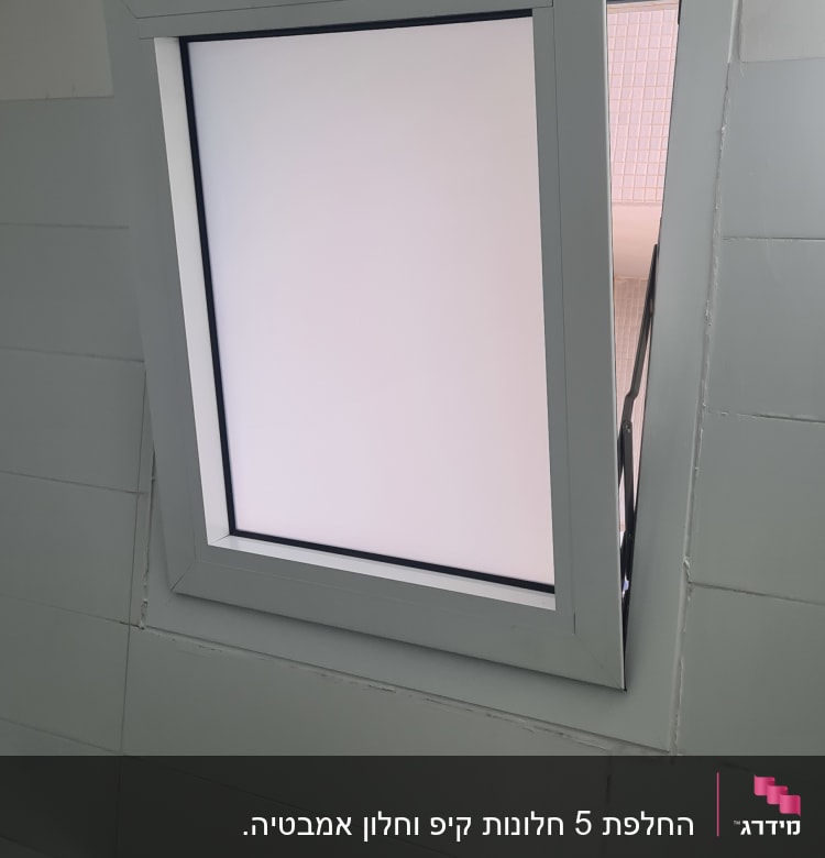 חלון אלומיניום עם מסגרת אפורה על קיר לבן